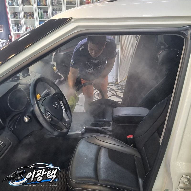 흰색 차량 운전석 문을 열고 실내를 스팀으로 세정하는 모습