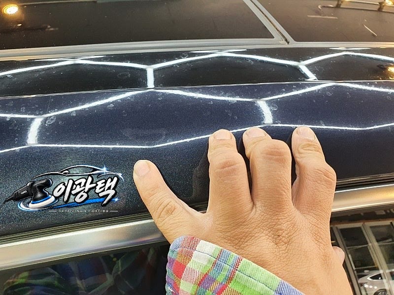 손가락 옆으로 하얀 반점이 묻어 있는 남색 차량 도장면